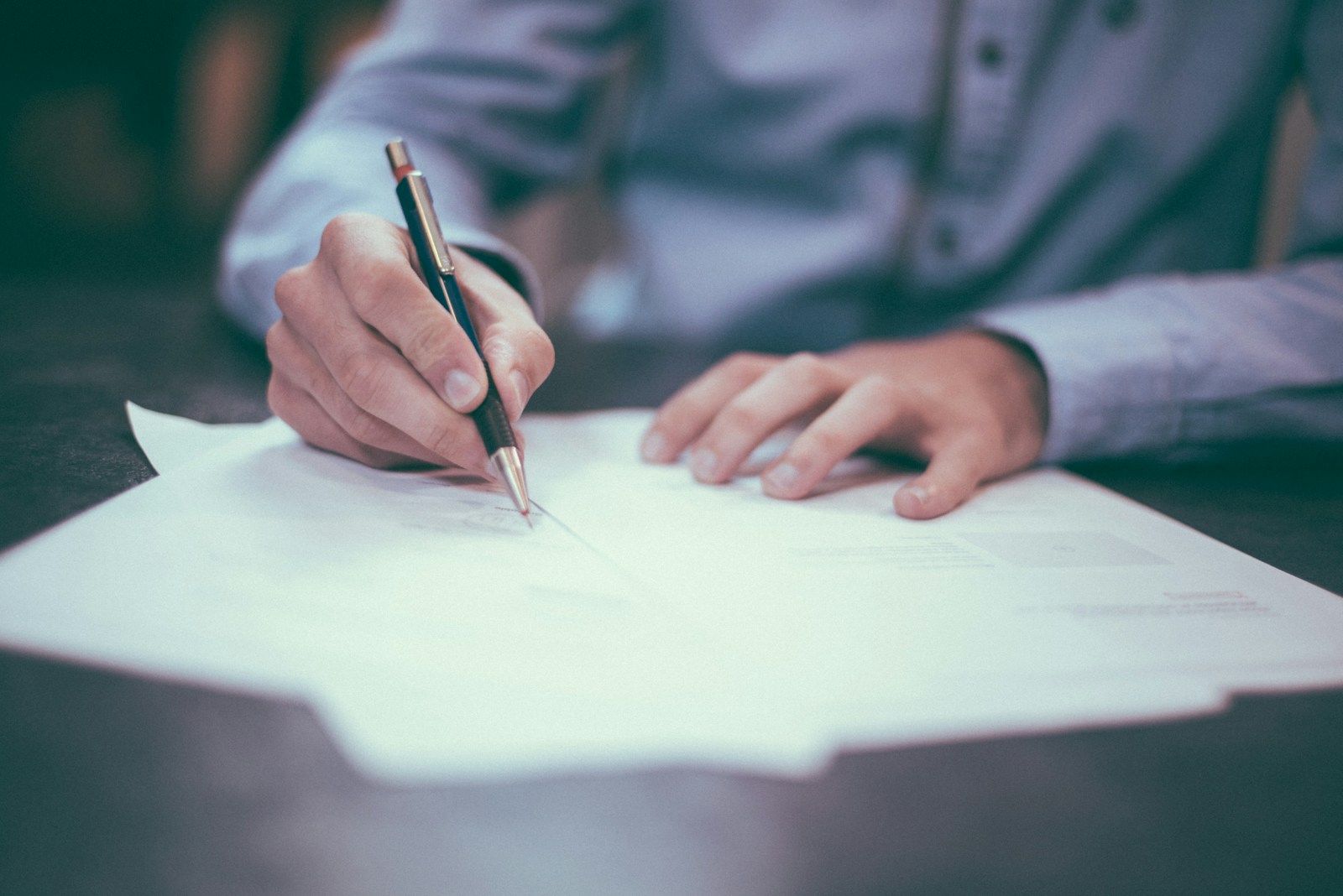 A person signing loan paperwork at a desk